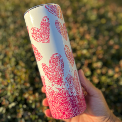 20oz Stainless Steel skinny tumbler with falling pink hearts and a white background and includes a silicone bottom, leakproof top, metal straw and straw cleaner.