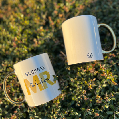 A set (2) 11oz white ceramic mugs with gold handles and shows the back of the mug with displays the Unique Effects logo.